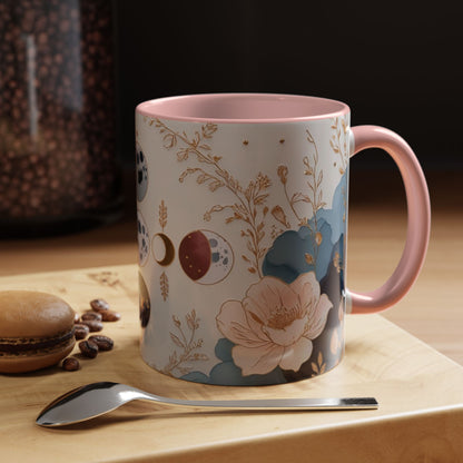 Mug with floral design on a wooden surface with coffee beans and a spoon.